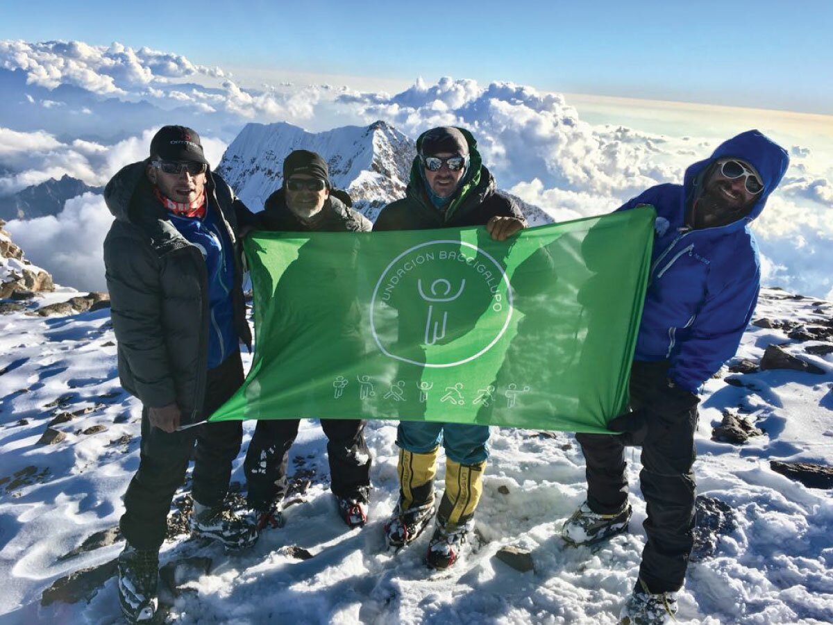 Ezequiel, Julián, Guille y Ulises con la bandera de la fundación Baccigalupo en la cumbre